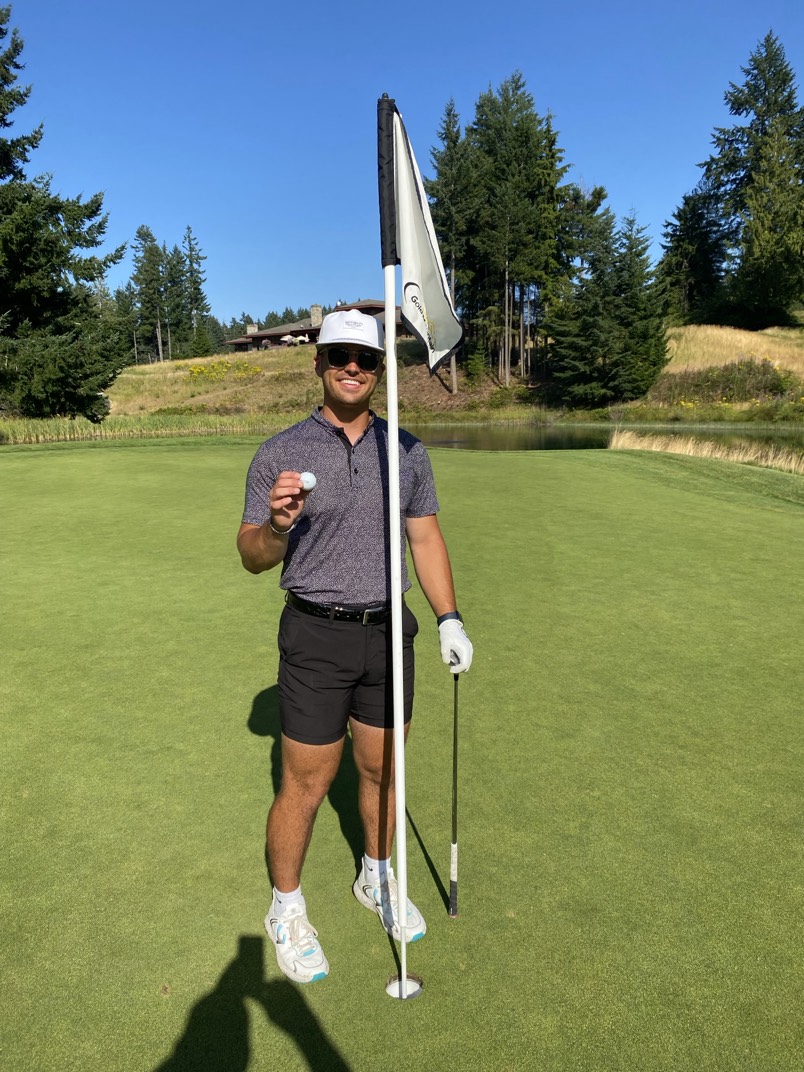 Micah Houston holding a golf ball beside the flagstick